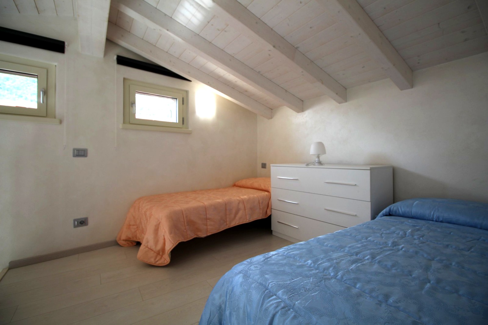 Zweites Schlafzimmer mit Einzelbetten und weißen Balken