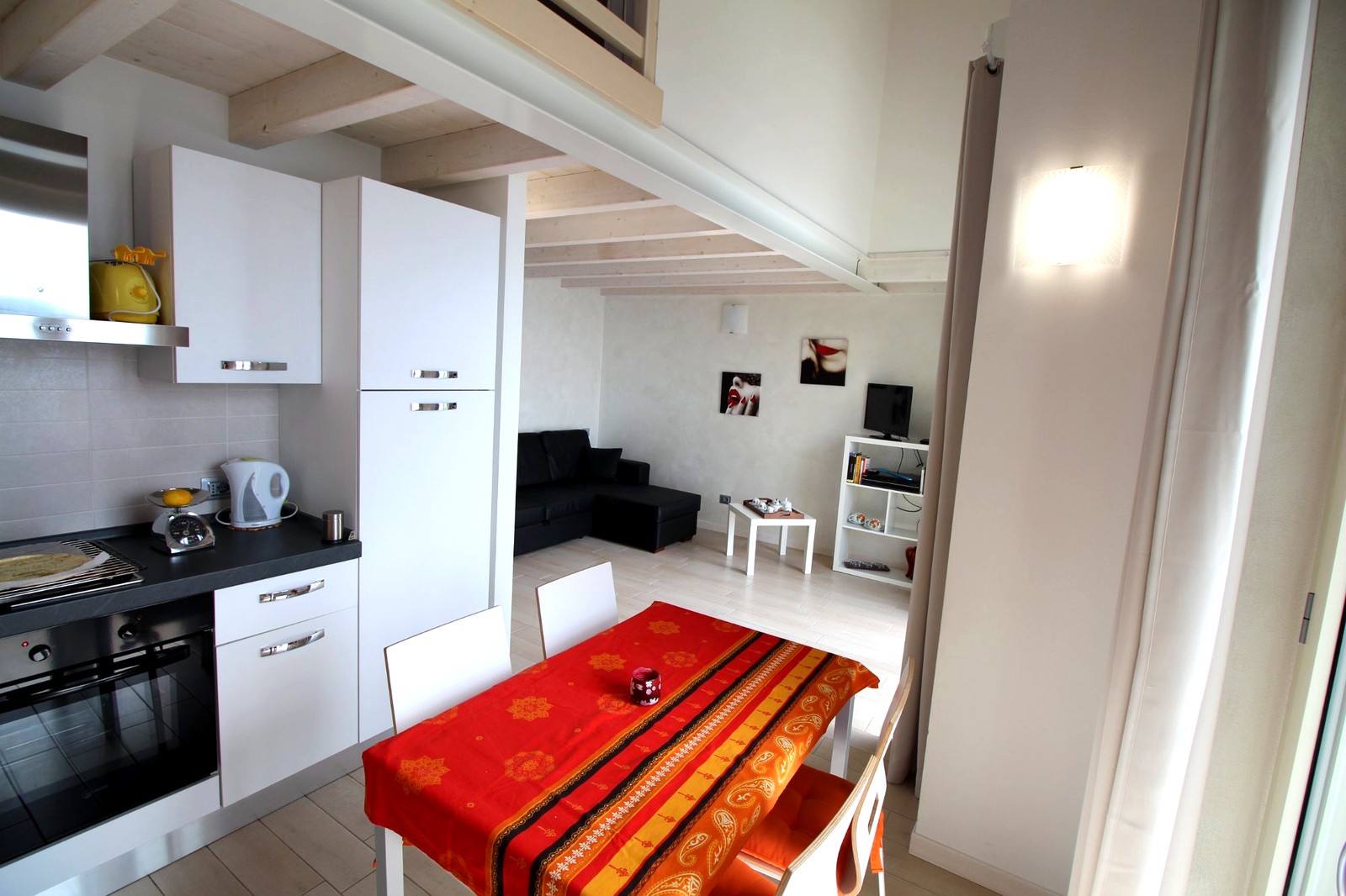 Cucina e soggiorno open space con travi bianche