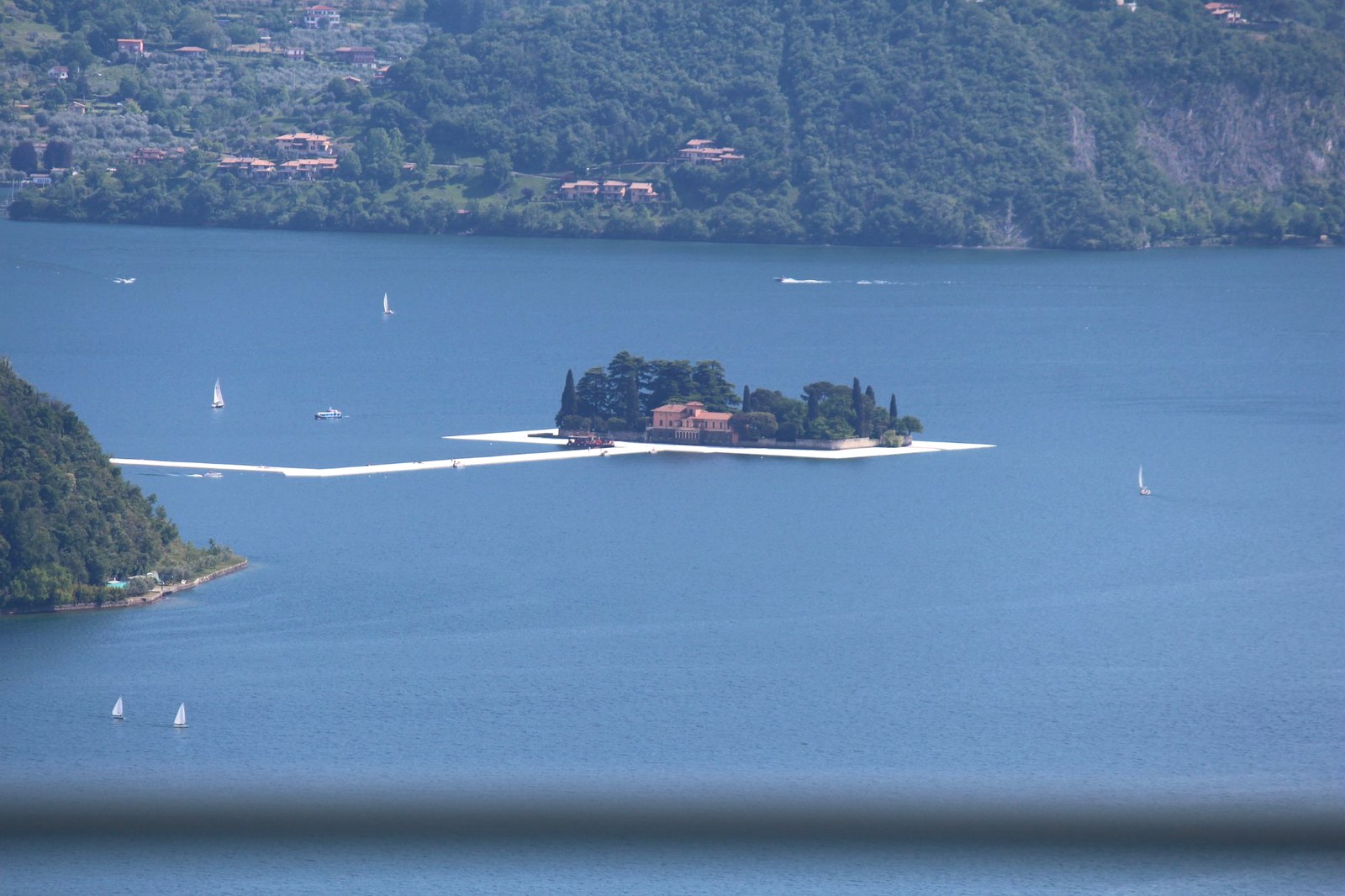 Lettini in vimini a bordo piscina con vista lago