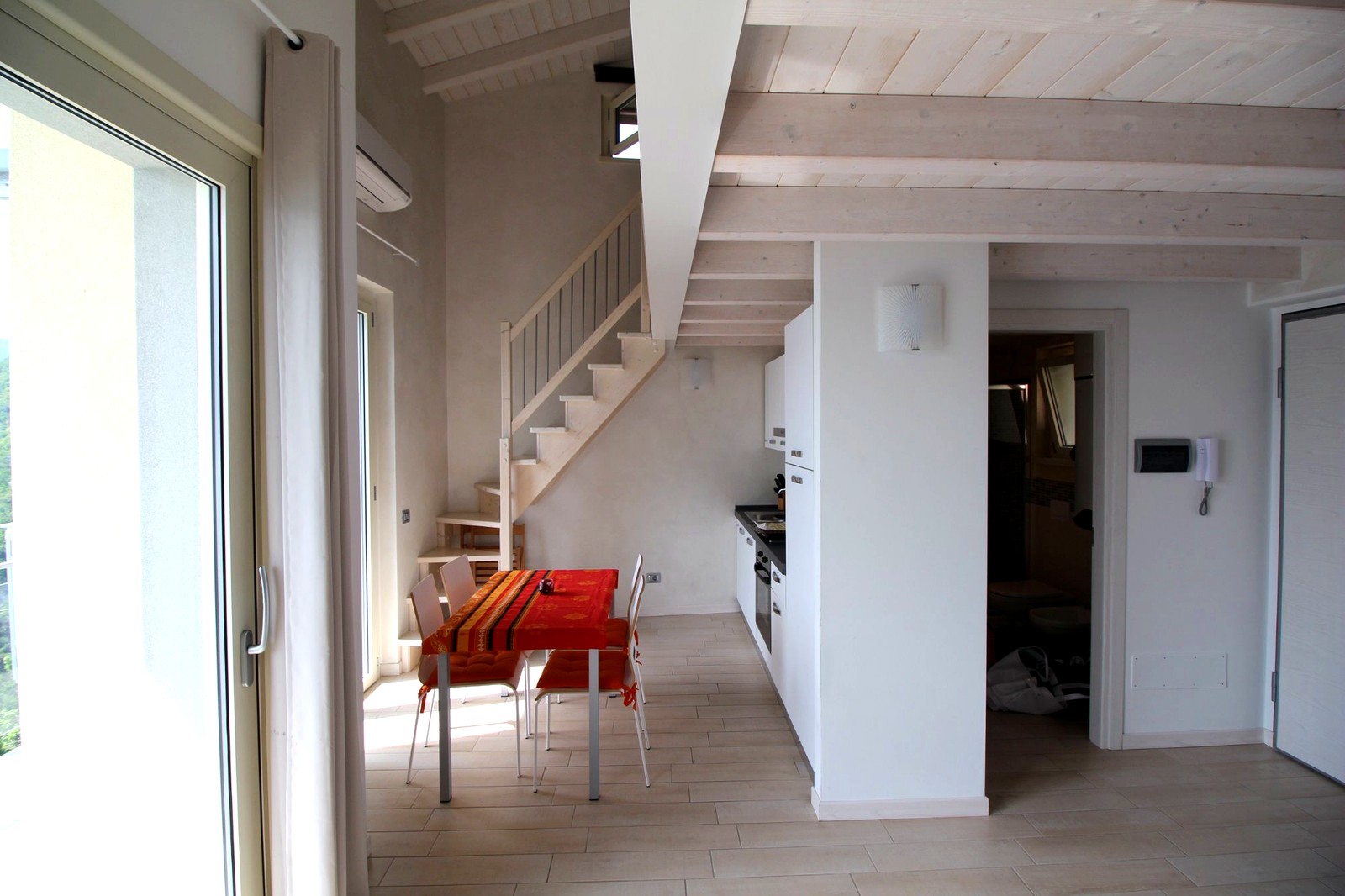 Soggiorno con scala interna in legno bianco e travi a vista