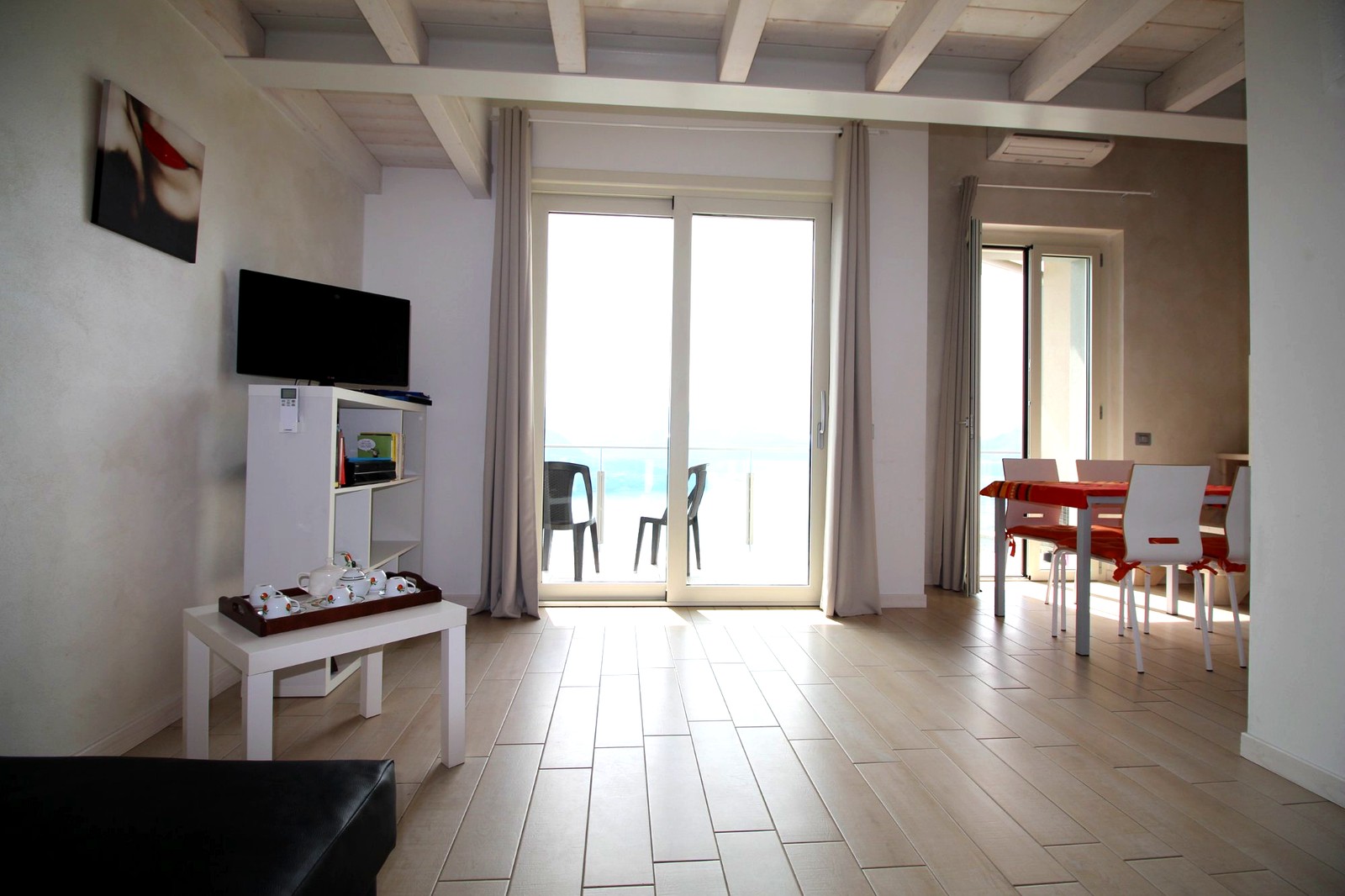 Helles Wohnzimmer mit weißen Sichtbalken und Terrasse zum See