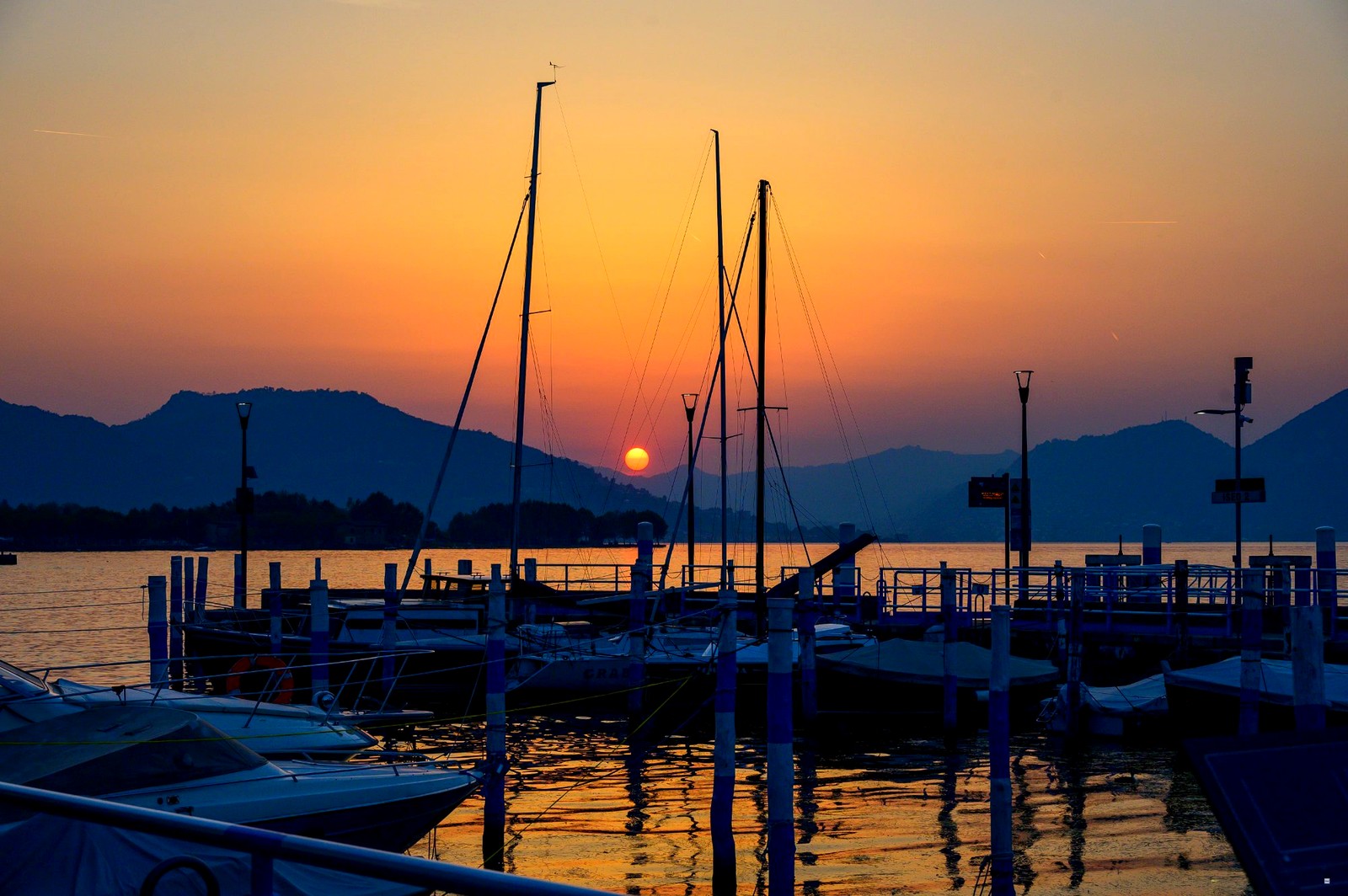 Tramonto arancio nel porto del Lago d'Iseo con barche a vela