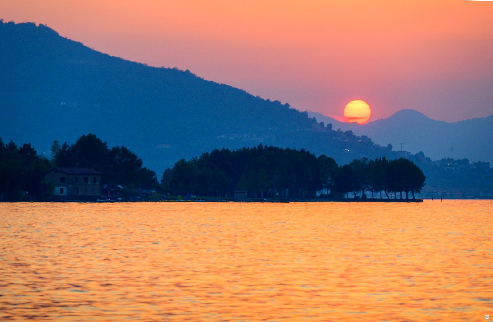Tramonto arancio con sole che tocca la montagna